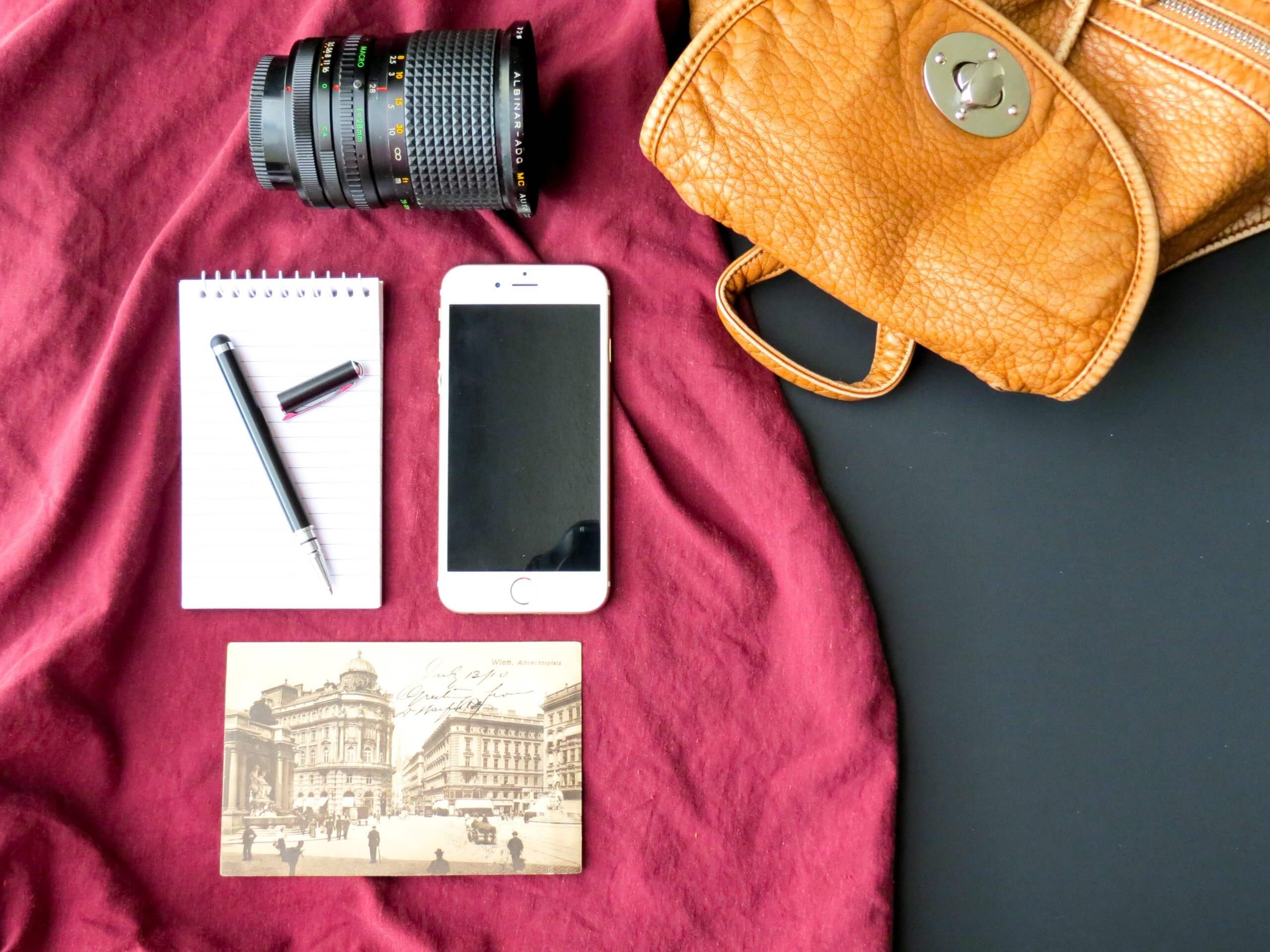 Spullen in een backpack, namelijk: smartphone, pen, cameralens en foto.